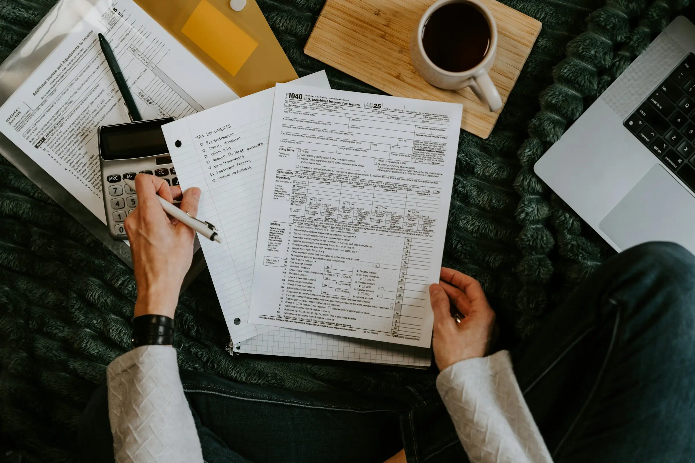 Person reviewing tax forms with a calculator and pen