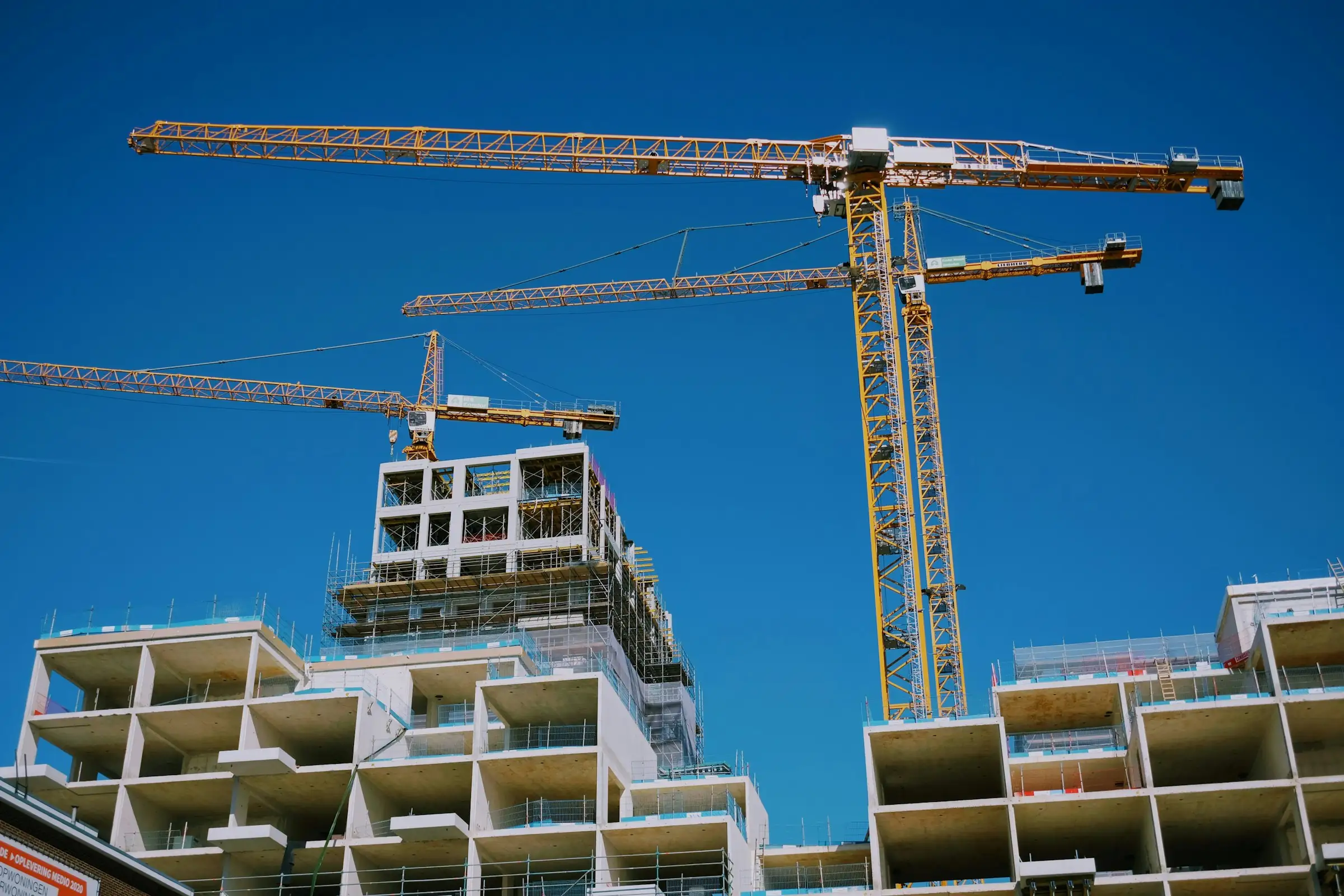 Tower cranes above a concrete commercial building under construction