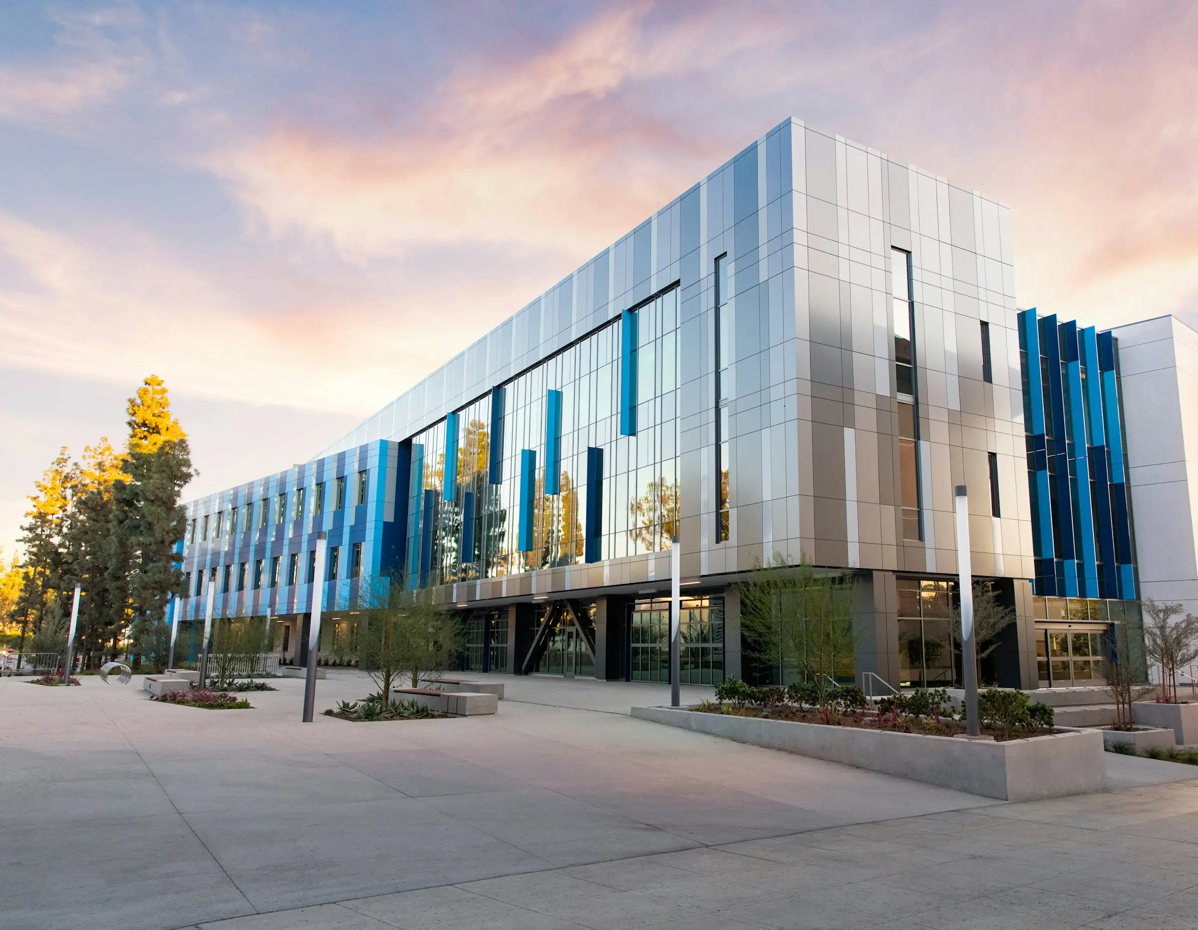 Modern glass office building and plaza at sunset
