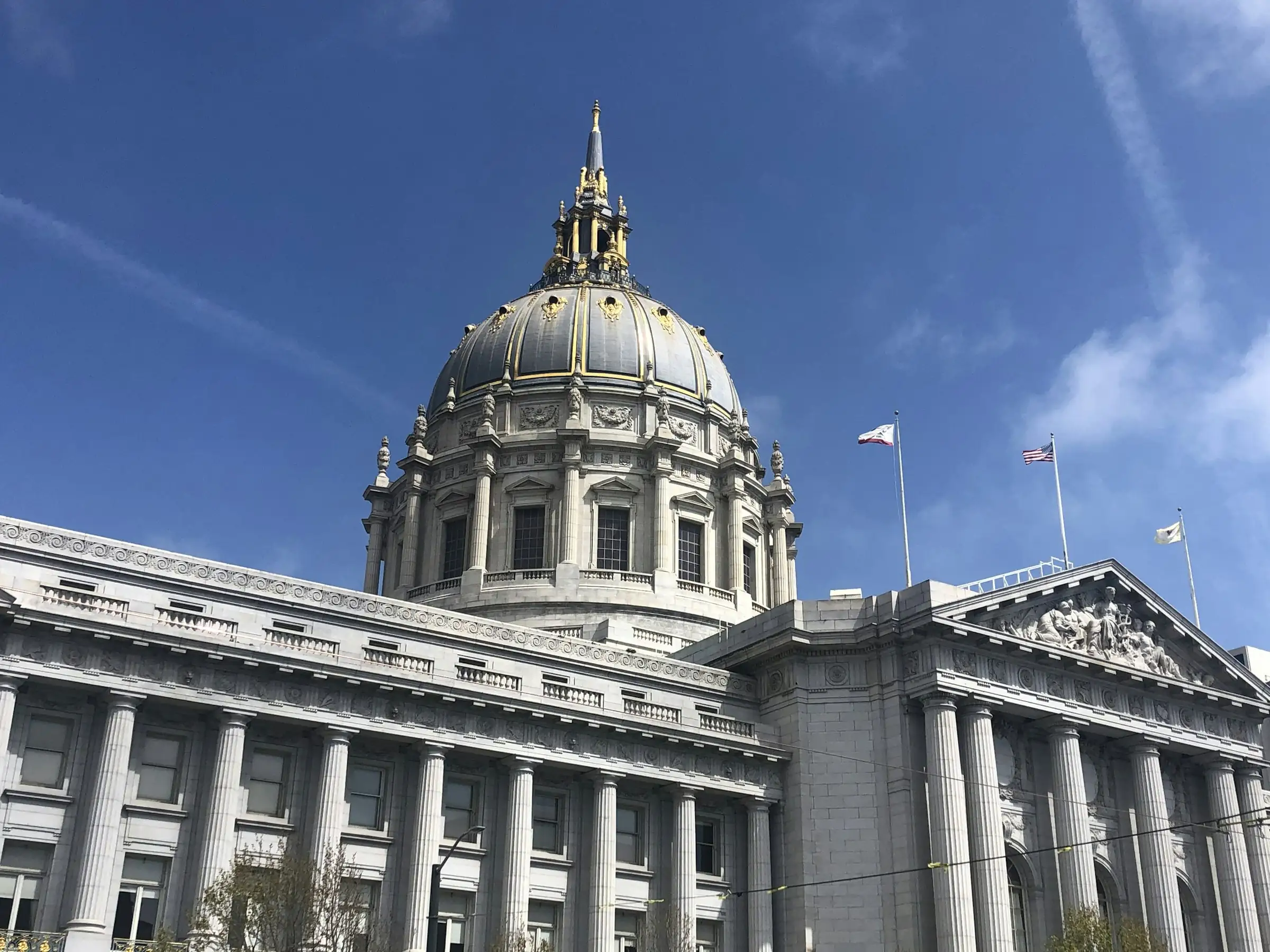 Domed city hall building with flags under a blue sky