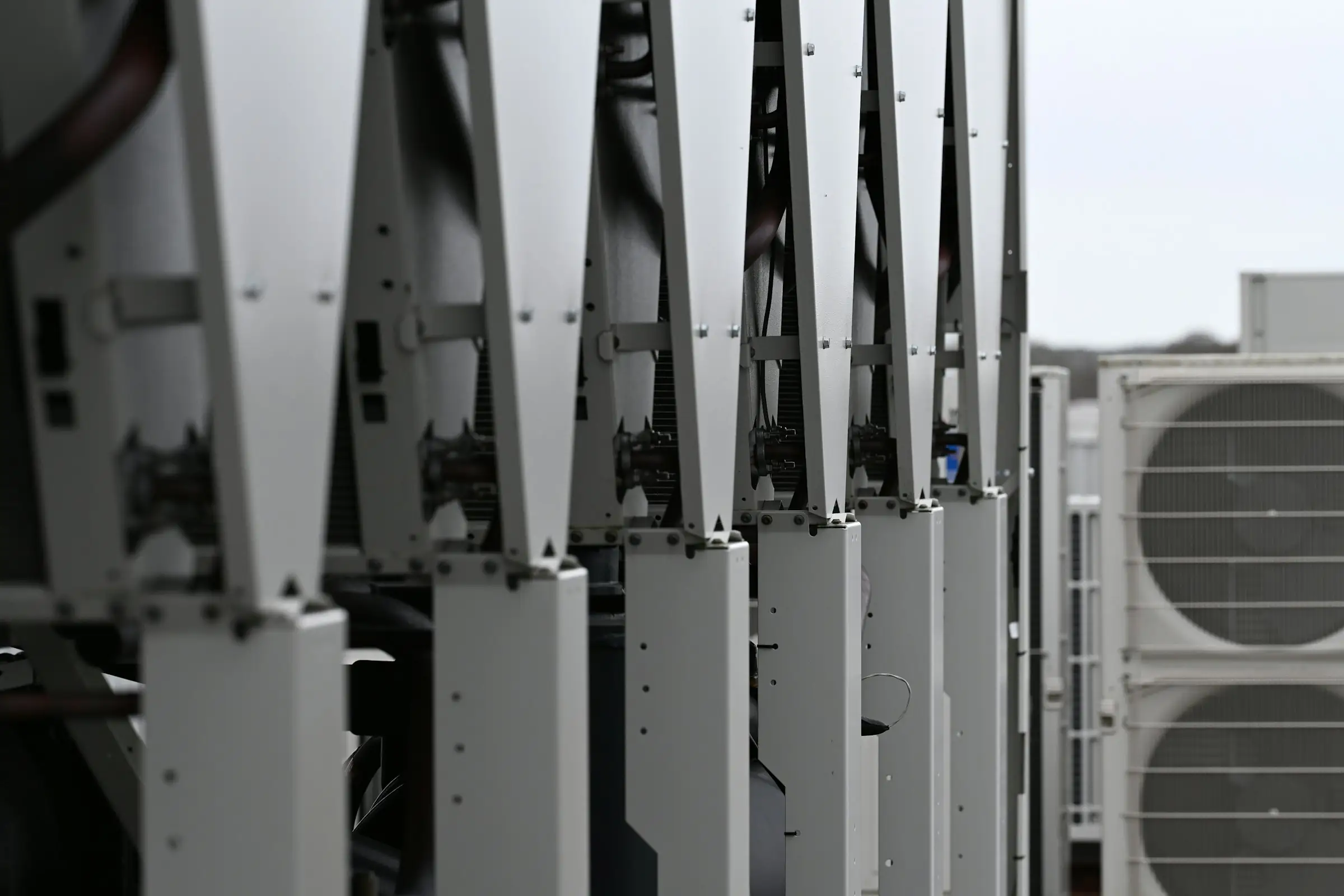 Row of rooftop HVAC condenser units on mounting frames