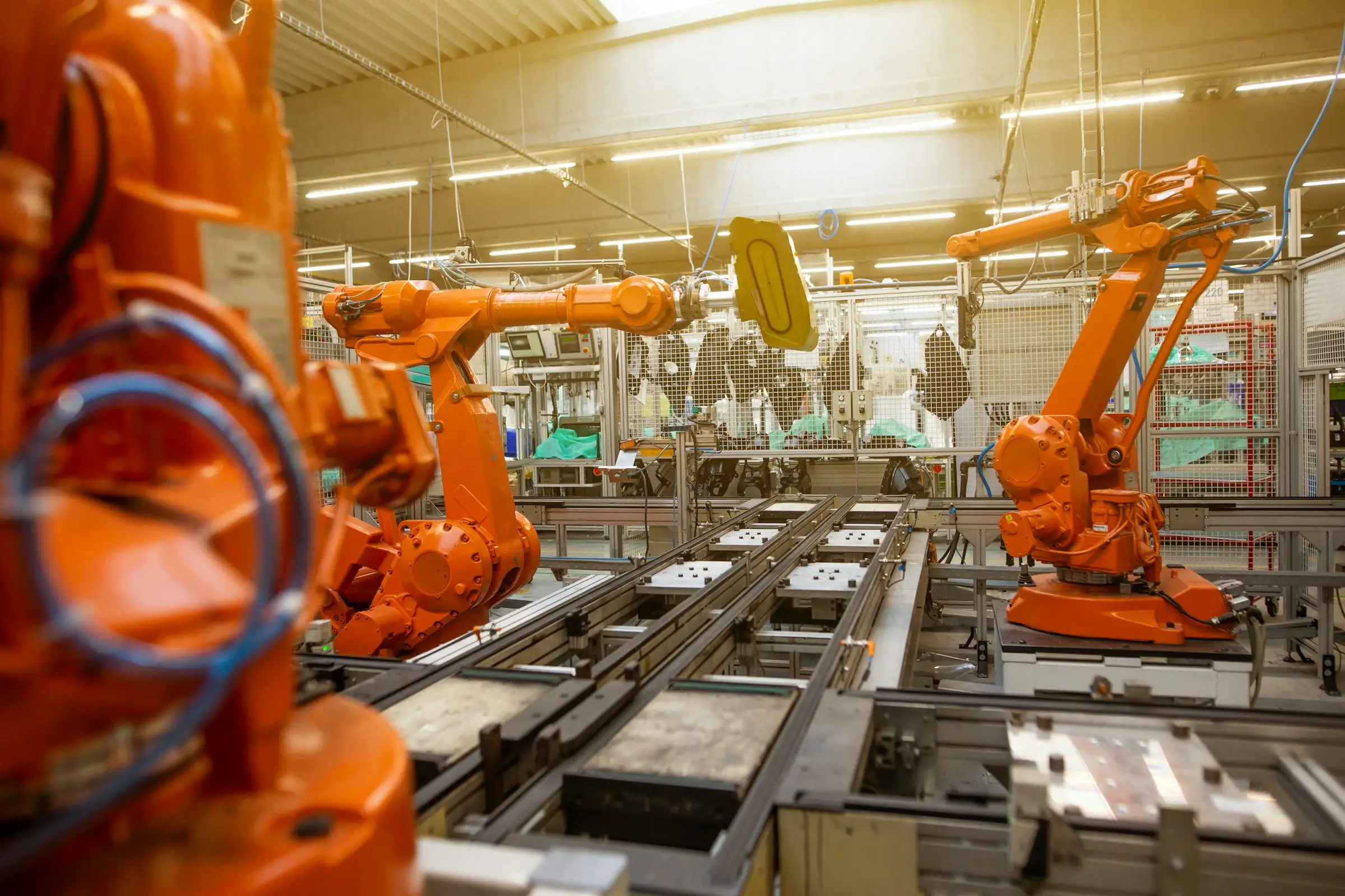 Orange industrial robot arms working on a factory line