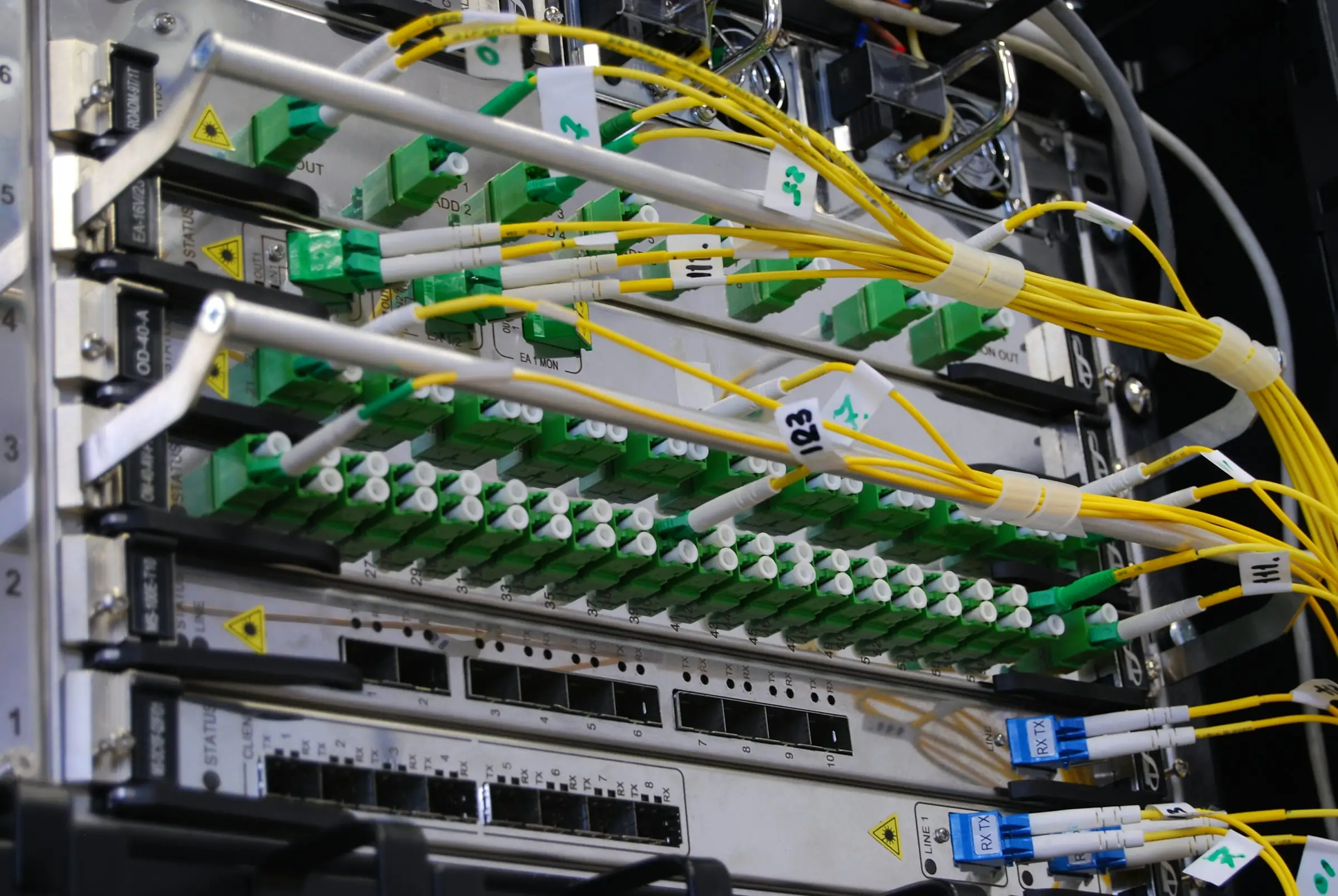 Fiber optic cables plugged into a network patch panel in a server rack