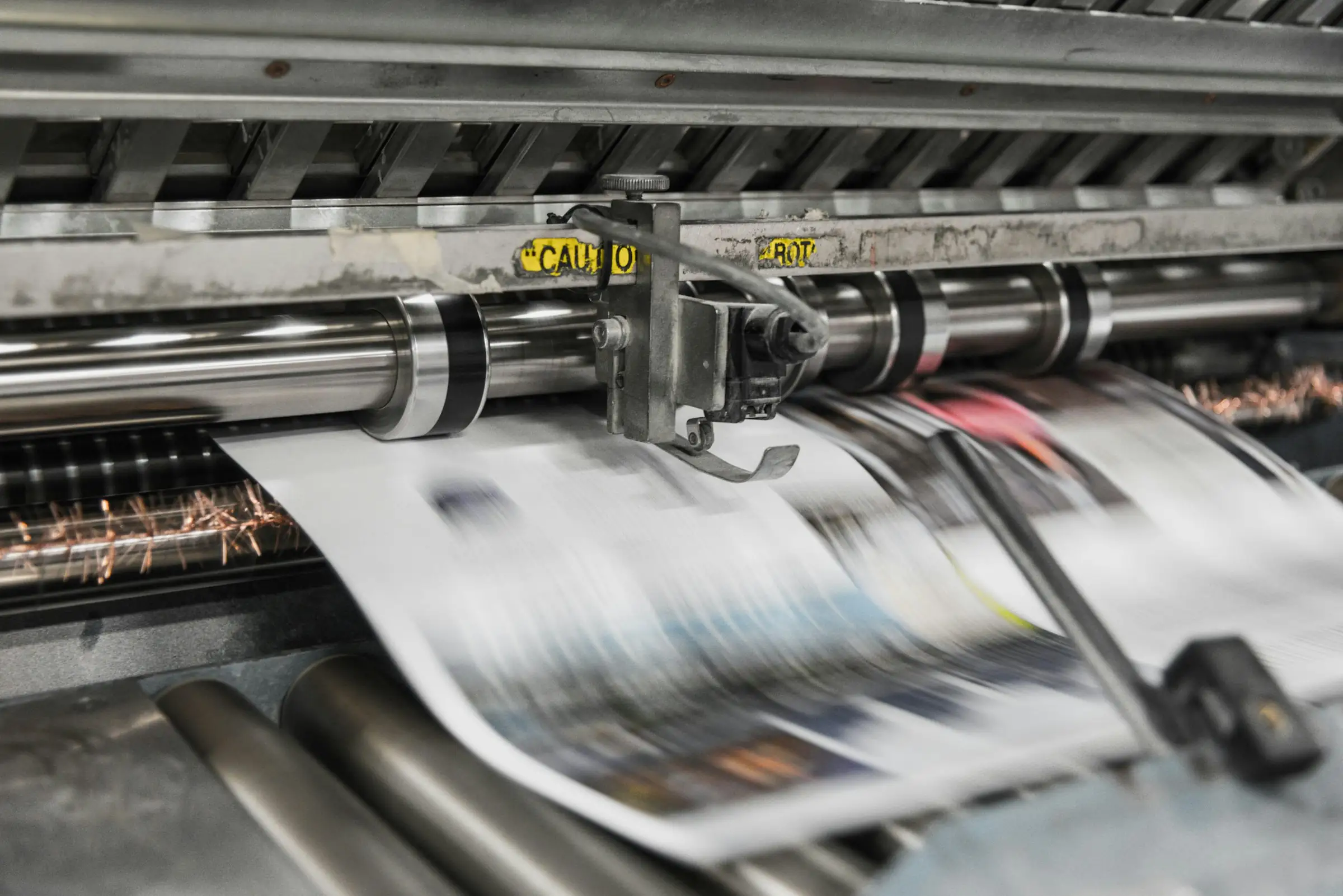 Printed paper running at speed through a commercial printing press