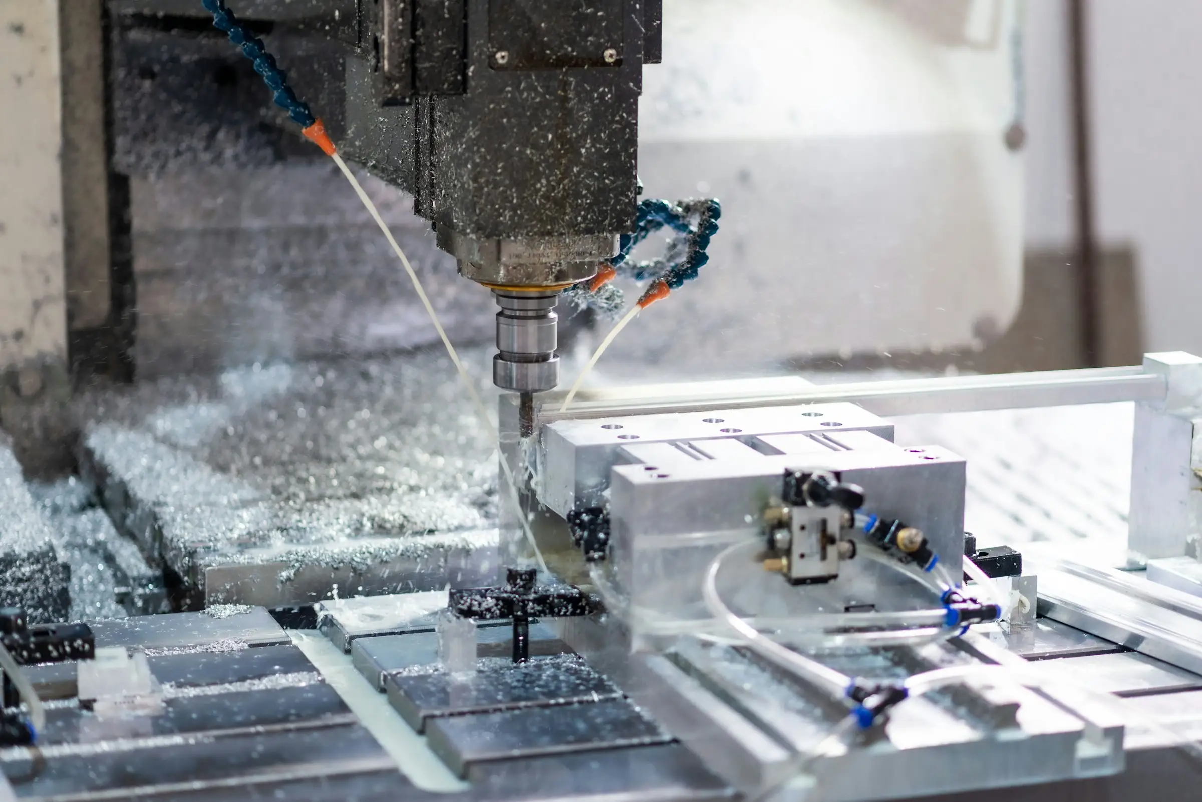 CNC mill cutting an aluminum part with metal chips and coolant