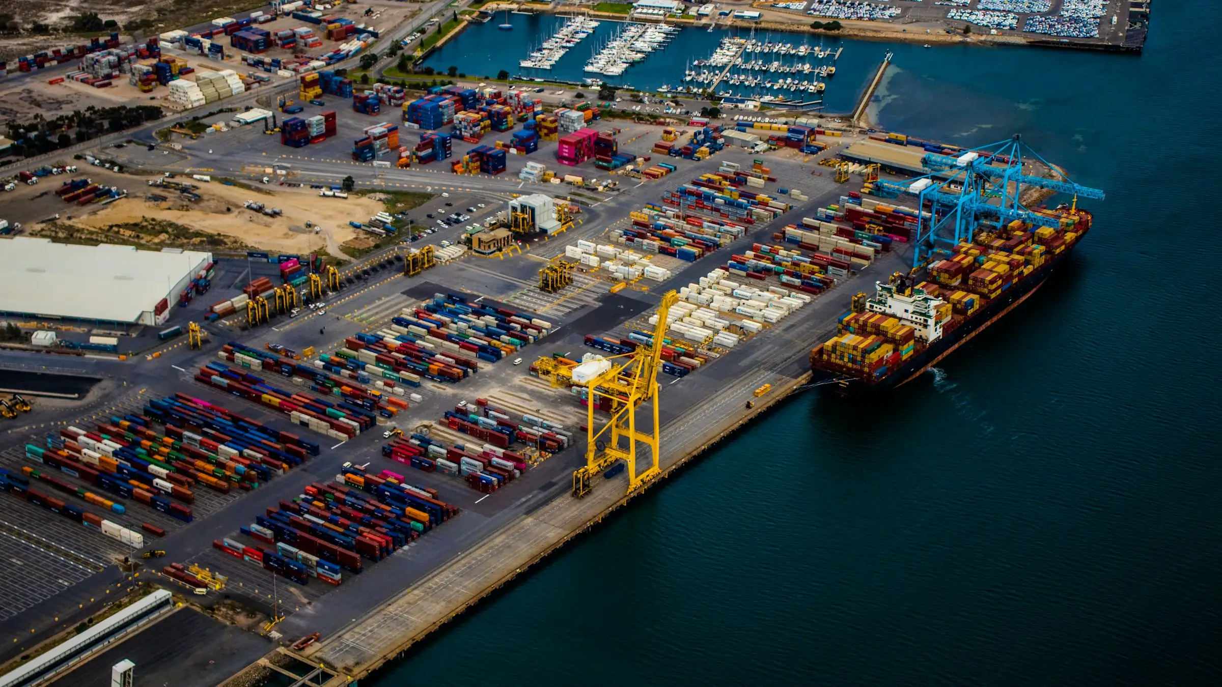 Aerial view of a container port with a cargo ship docked at the cranes